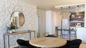 Une cuisine moderne avec des meubles blancs, un îlot central et des tabourets de bar.