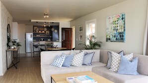 Un salon moderne avec un canapé, une table basse et une cuisine en arrière-plan.