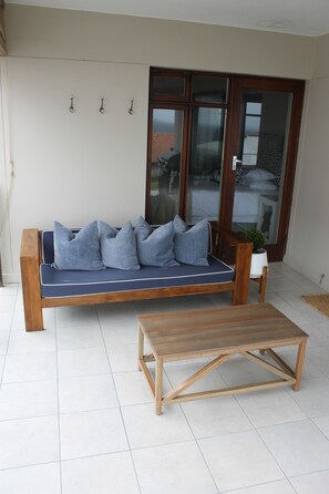 Relax in this cozy outdoor seating area with a comfortable bench and sofa, perfect for unwinding.