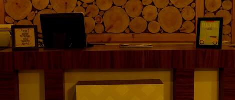 A reception desk with a wall of stacked logs behind it.