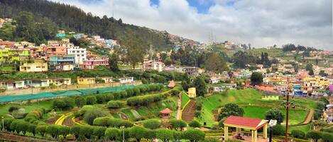 Un pueblo en la ladera de una colina con casas escalonadas y un jardín central con senderos y un pabellón.