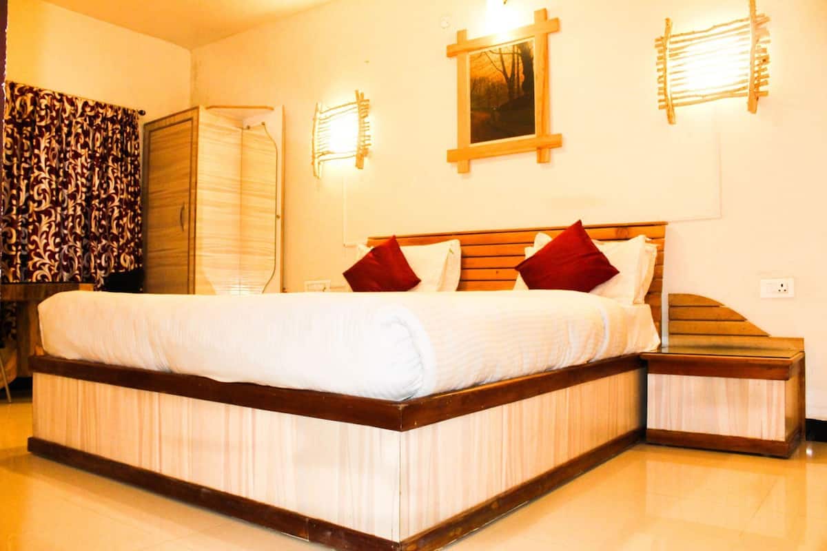 Une chambre d’hôtel avec un grand lit, une tête de lit en bois, une table de chevet, une armoire et un tableau accroché au mur.