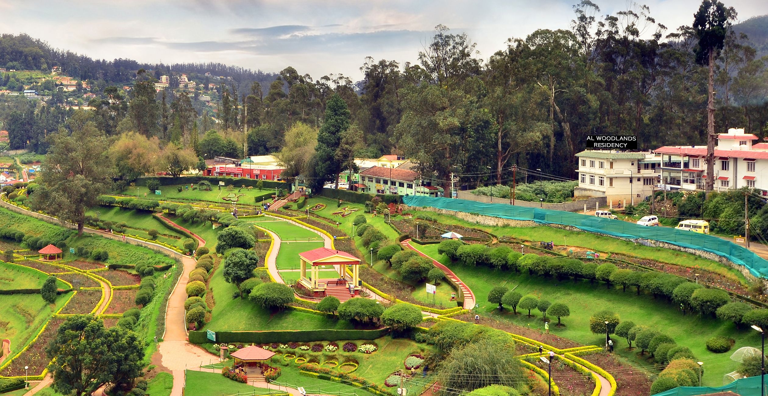 A residential area with a park, a gazebo, and a large building labeled "WOODLANDS RESIDENCY".