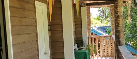 A covered outdoor area with wooden walls, a tiled floor, and a table with a green tablecloth.