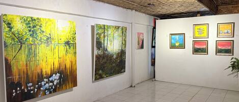 Una galería de arte con pinturas en las paredes y un piso de baldosas.