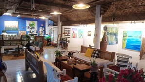 A cozy interior with a thatched ceiling, wooden furniture, and artwork on the walls. - La Vida Hostel (Samal)
