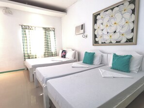 A hotel room with two beds, a window with curtains, a wall-mounted air conditioner, and a framed floral artwork. - La Vida Hostel (Samal)