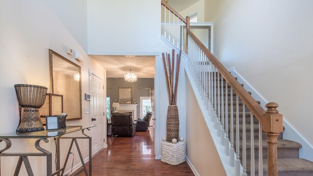 A hallway with a glass table, a mirror, and a staircase with wooden railings. - Comfort and Style on the Colonnade (Rex)
