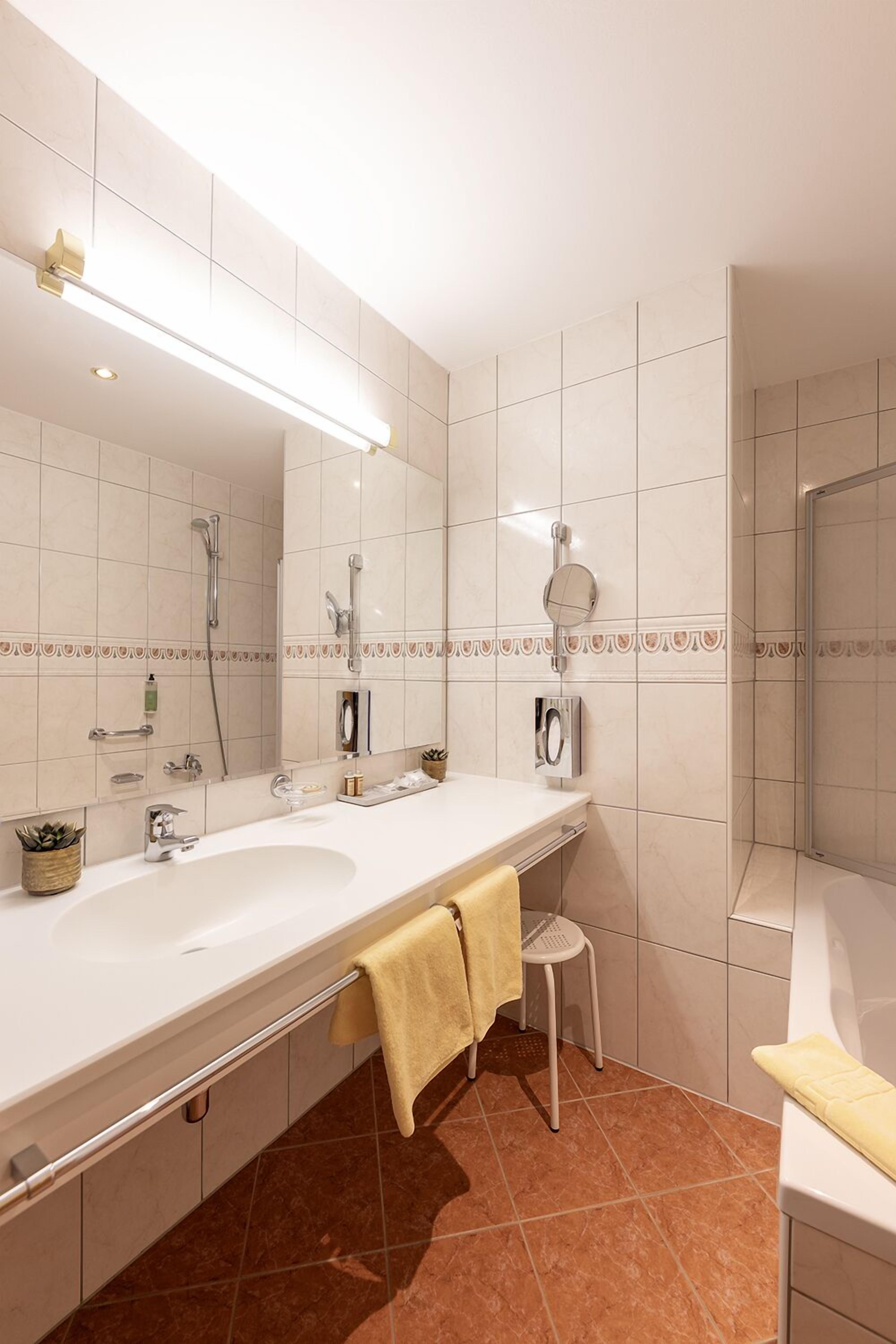 A modern bathroom with a large mirror, two sinks, a shower, and a towel rack.