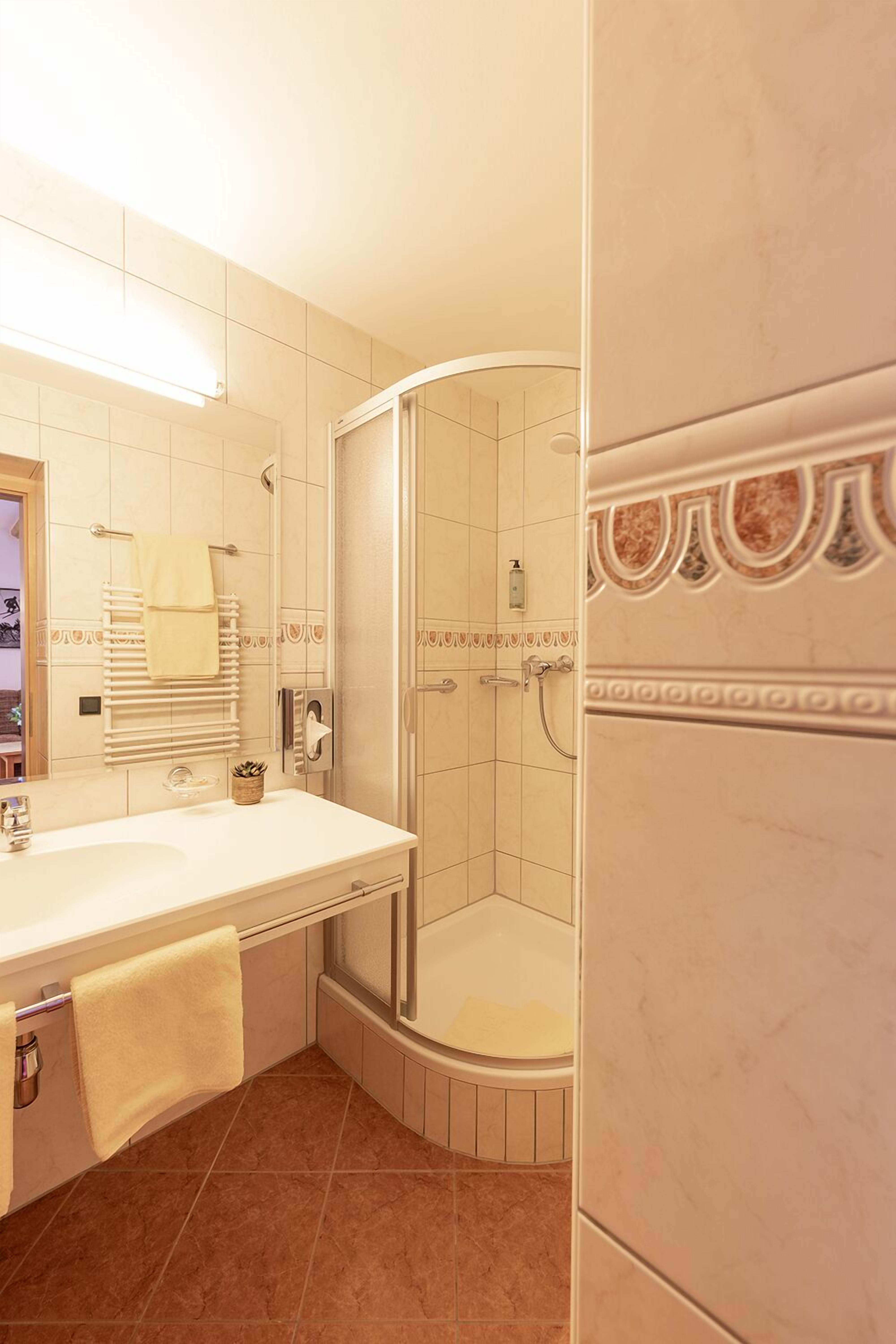 A bathroom with a white sink, a mirror, a towel rack, and a shower area.