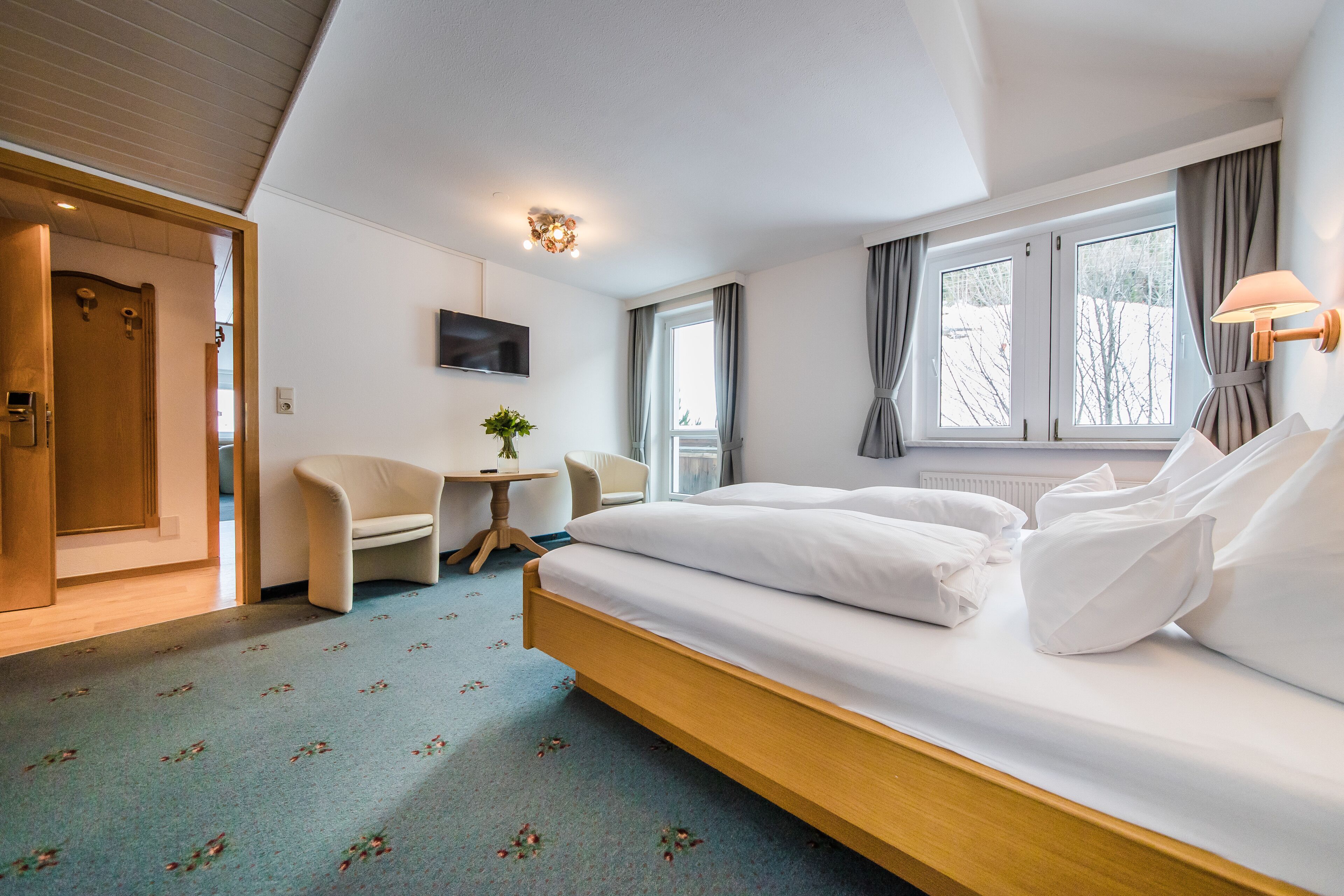 Une chambre d’hôtel avec un lit, un bureau, une chaise et un téléviseur fixé au mur.