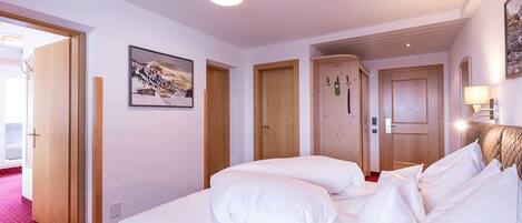 A hotel room with a large bed, two doors, a framed picture on the wall, and a red carpet.