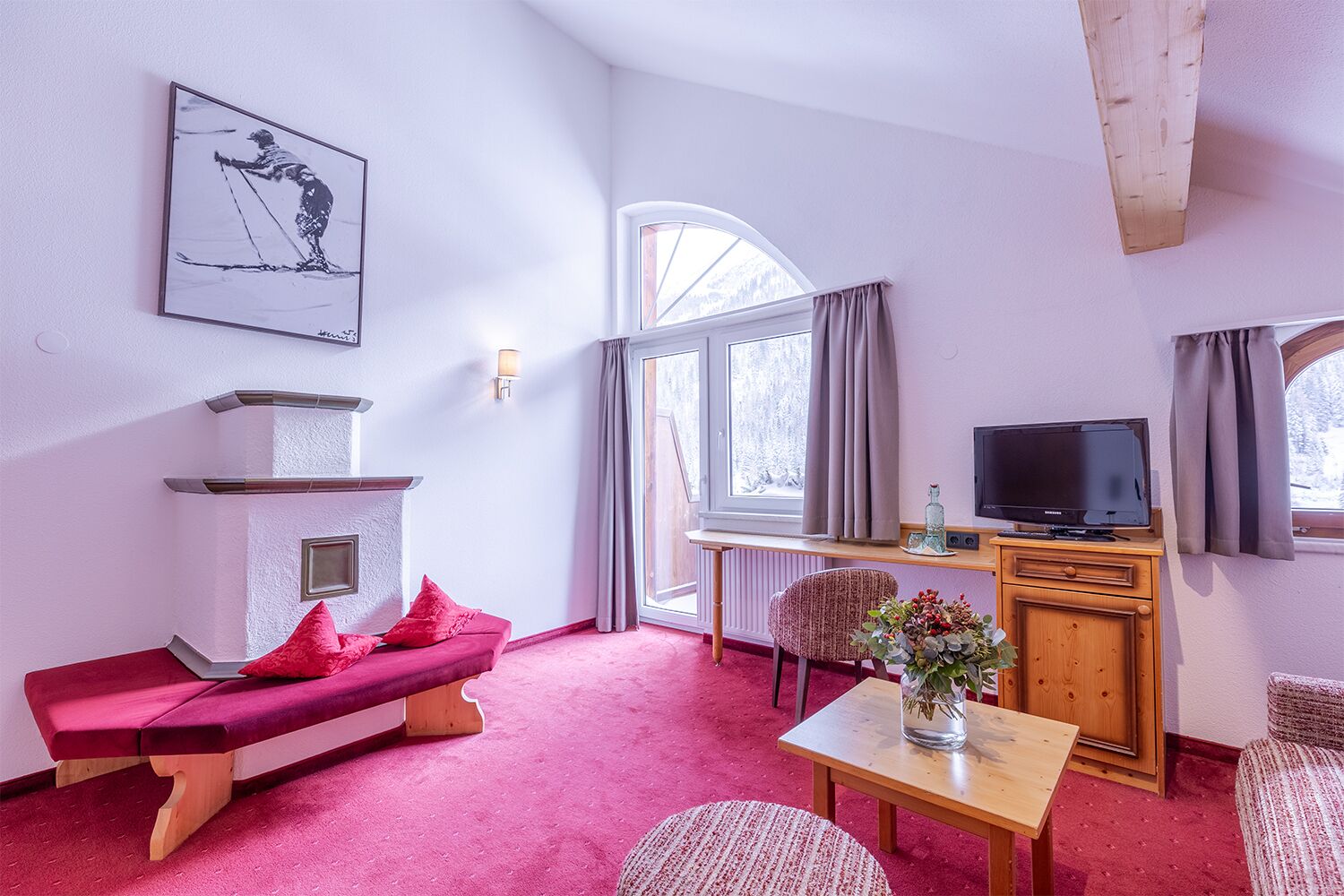 A cozy room with a fireplace, a television, a bench, and a window with curtains.