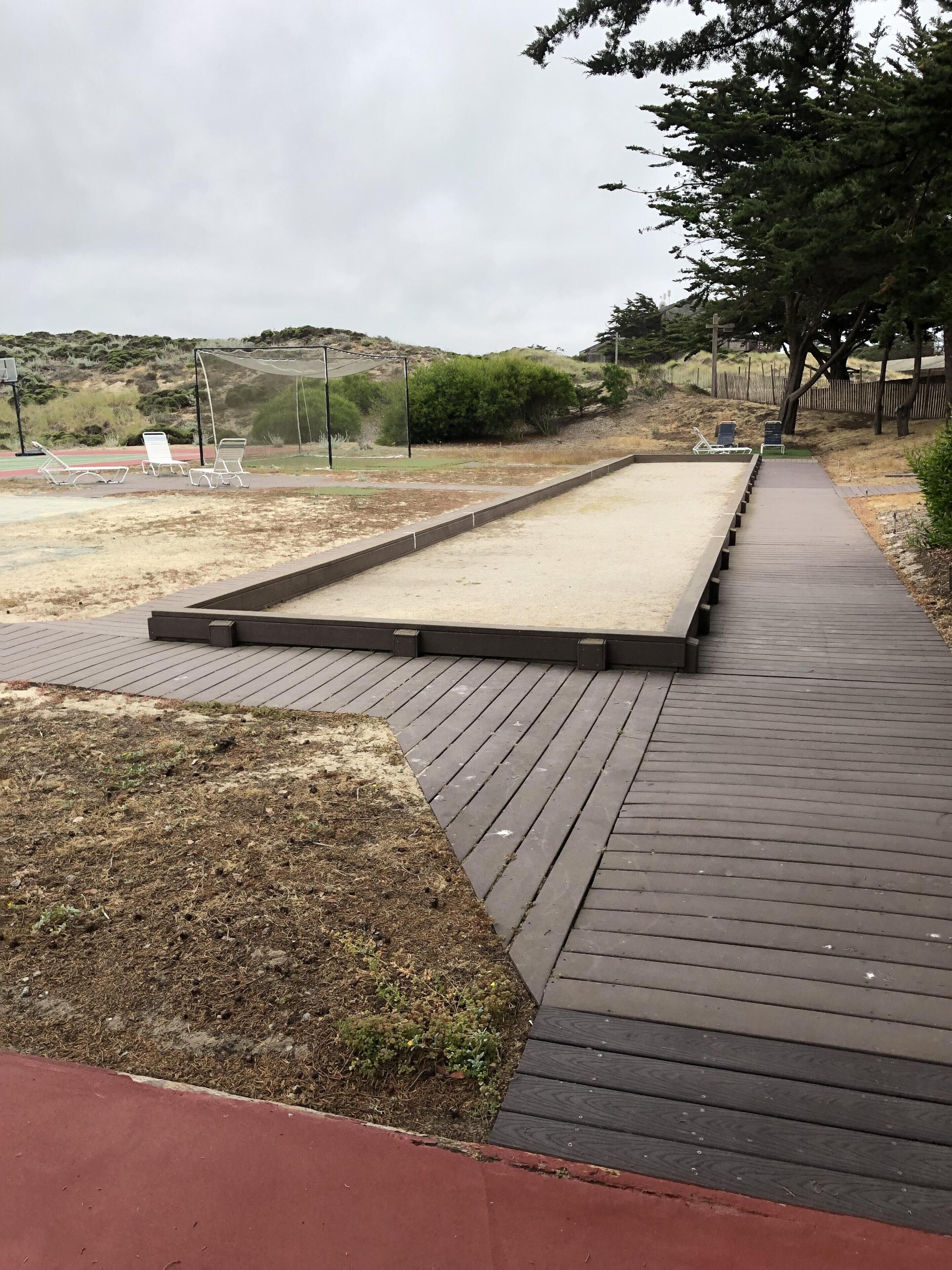 Une terrasse en bois avec un espace sablonneux et un chemin pavé.