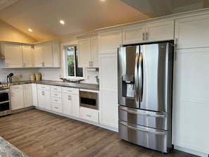 A modern kitchen with white cabinets, stainless steel appliances, and a wooden floor. - 3 Bedroom Ocean Front (sleeps 6) (Castroville)