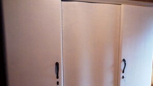 Une grande armoire blanche à deux portes et dotée de deux poignées.