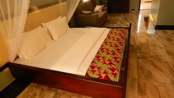 Una cama con dosel, un sofá y una colcha estampada.