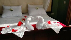 Una cama con ropa blanca, dos almohadas y un ramo de flores.