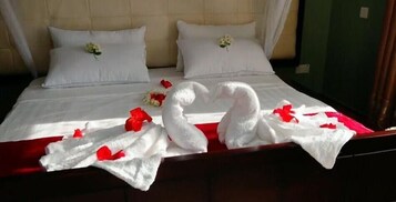 Una cama con ropa blanca, dos almohadas y un ramo de flores.
