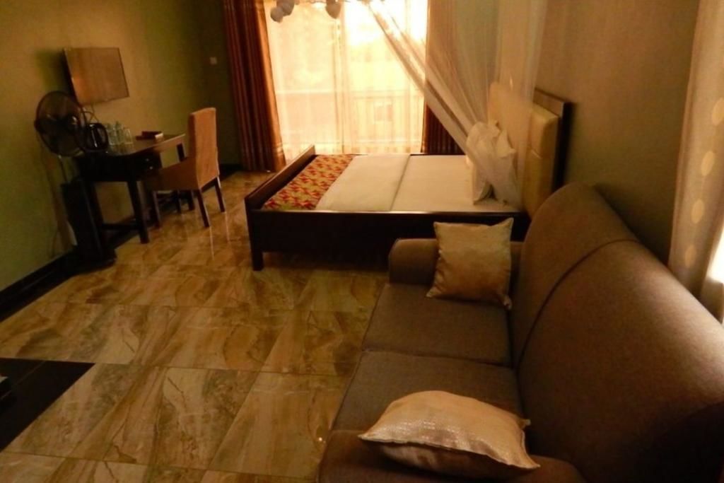 Une pièce comprenant un lit, un canapé, une petite table avec des chaises et une fenêtre avec des rideaux.