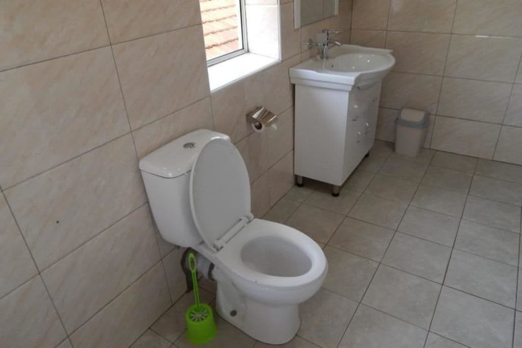 Un baño con inodoro, lavamanos y ventana.