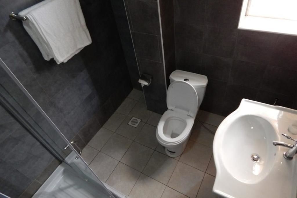 Et badeværelse med toilet, vask og bruser.