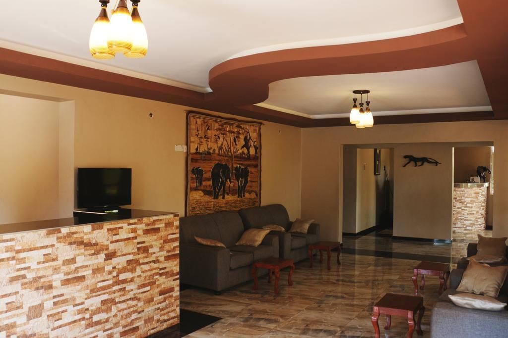 A spacious living area with a stone reception desk, a gray sofa, and a flat-screen TV.