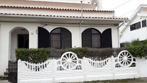 A building with a white facade, three arched windows with black shutters, and a white decorative fence with wheel designs. - Backpackers Hostel Fonte da Telha (Almada)