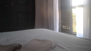 A room with a bed, a window with curtains, and a door. - Backpackers Hostel Fonte da Telha (Almada)
