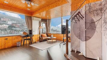 Una habitación con paredes y techo de madera, un sofá, una mesa y vistas a un paisaje urbano a través de amplios ventanales.
