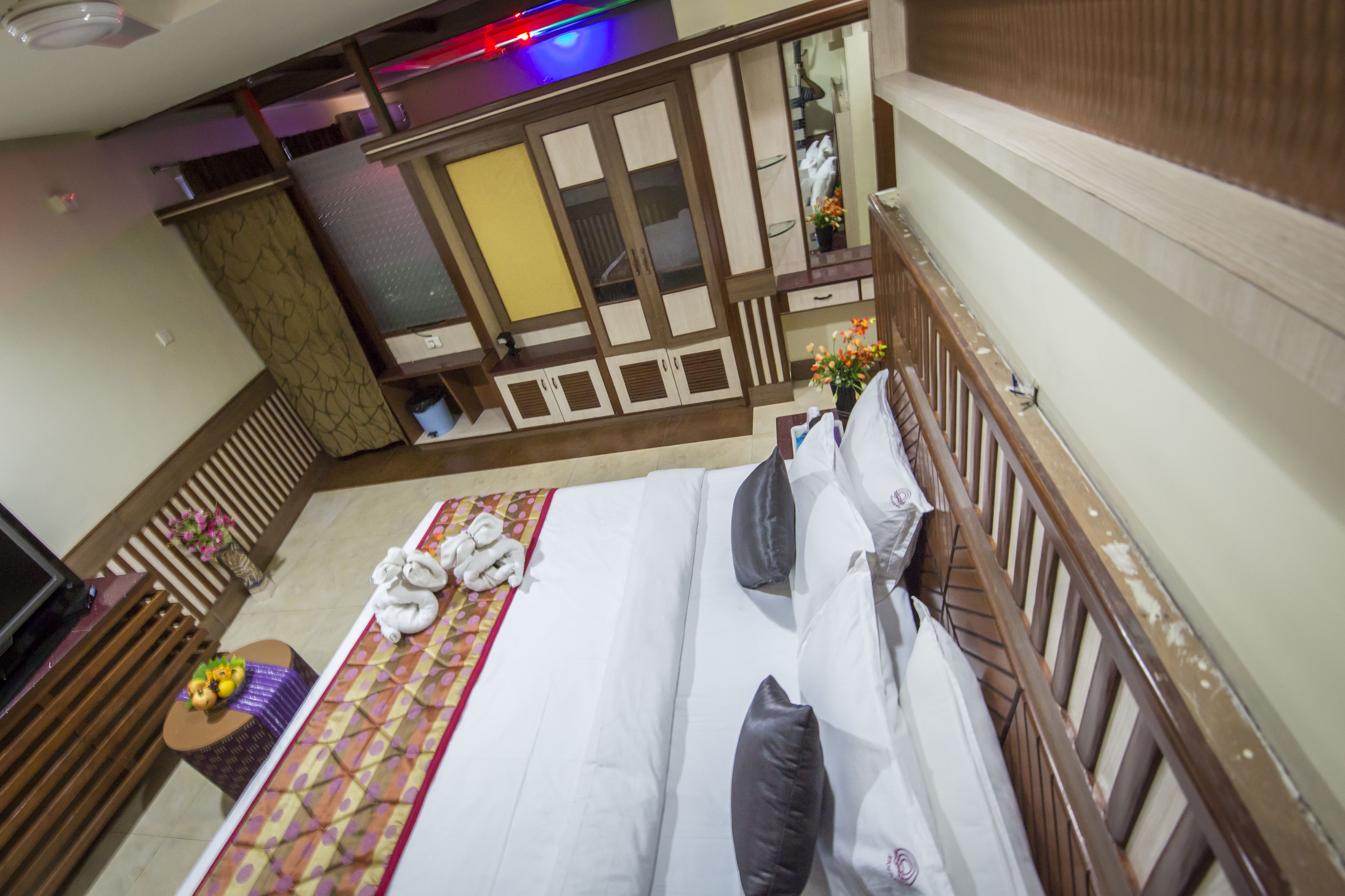 A bedroom with a large bed, wooden headboard, and a view of a balcony.