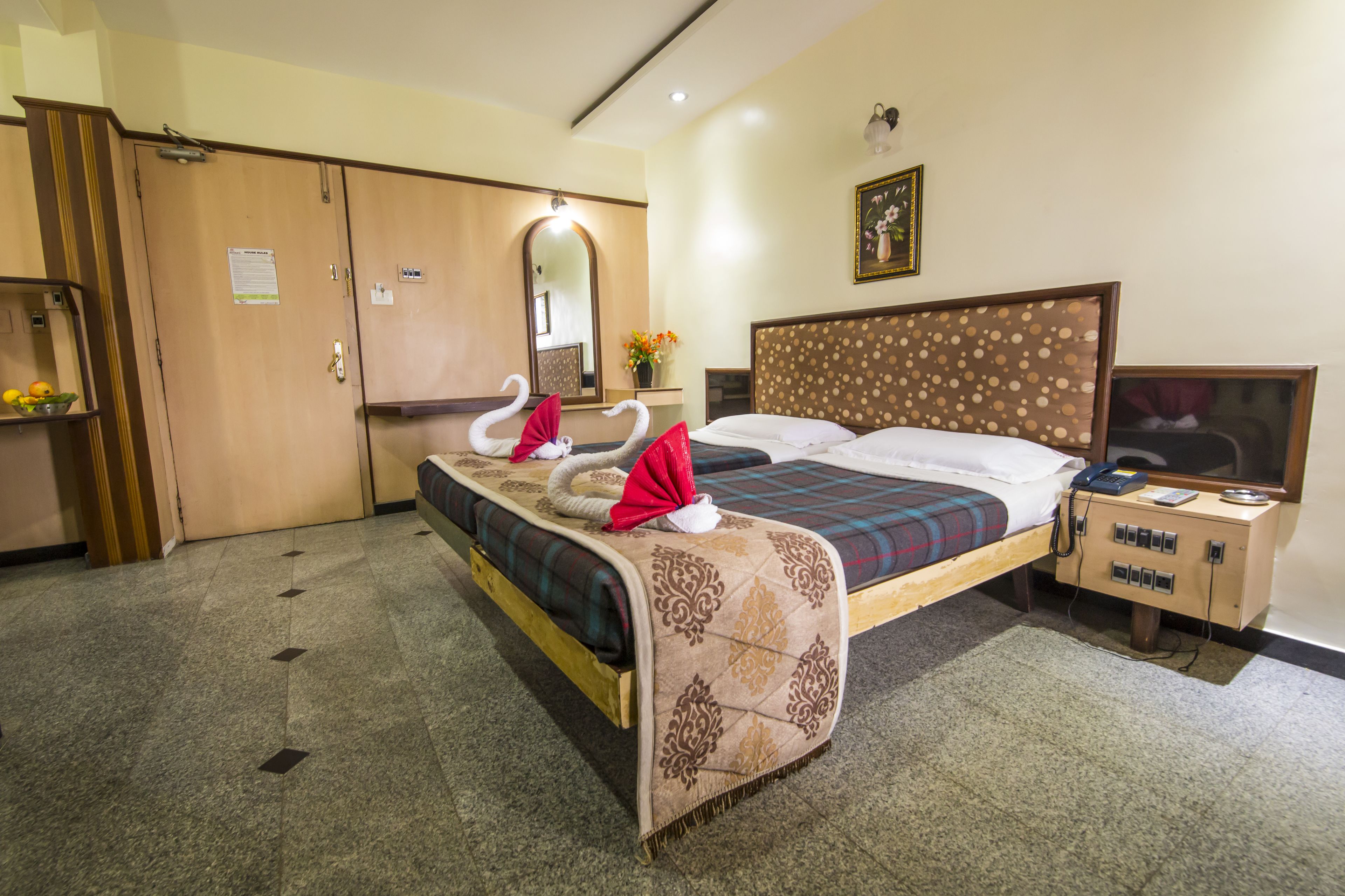 A hotel room with a bed, a nightstand, a wardrobe, and a mirror.