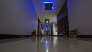 A long, narrow hallway with a reflective floor, leading to a staircase. - Hotel Aryaas (Tirunelveli)