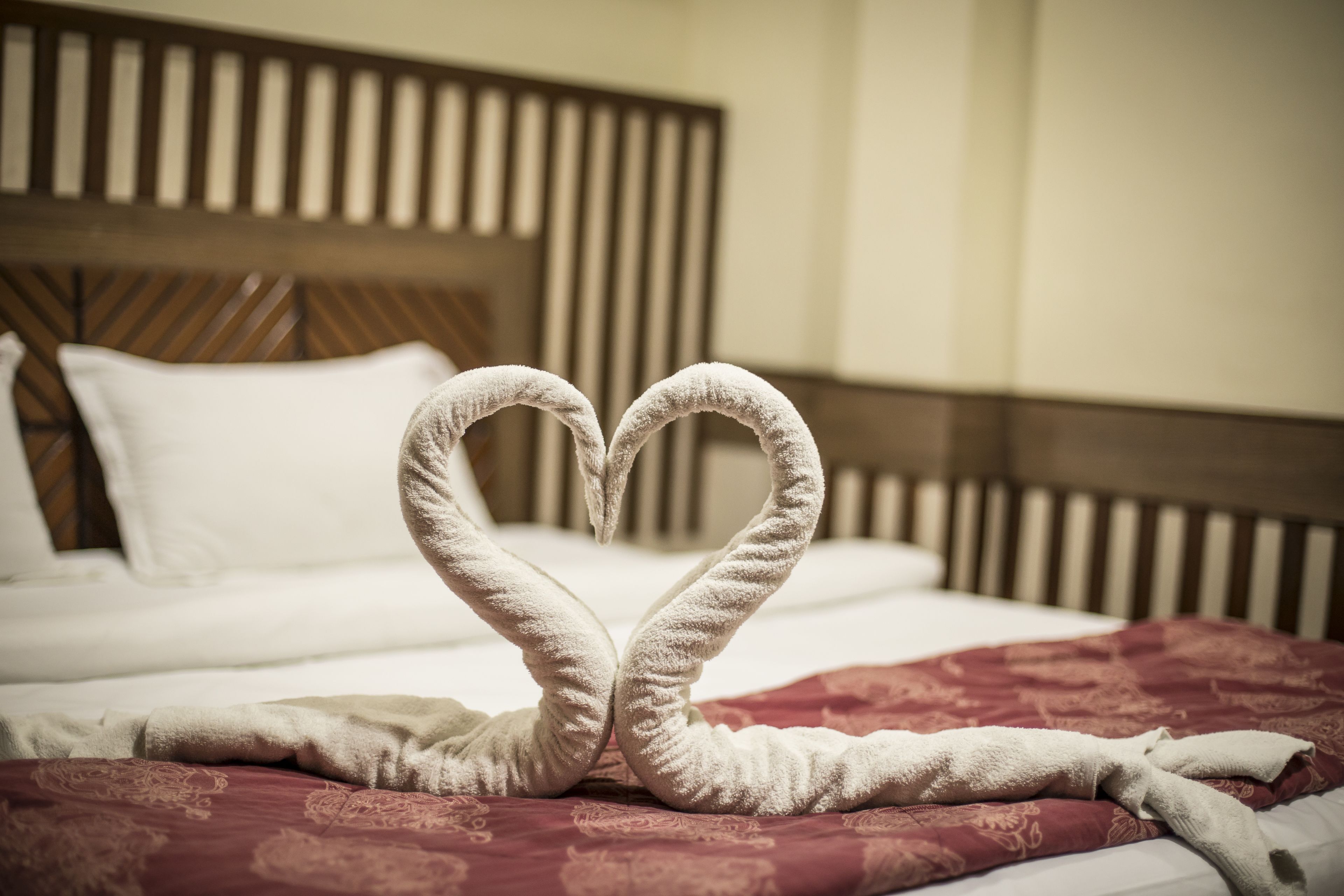 A bed with a heart-shaped towel arrangement on the bedspread.