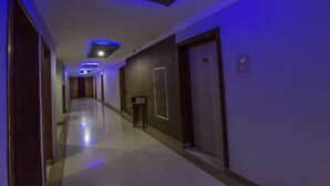 A hallway with a modern design, featuring recessed lighting and a clean, polished floor. - Hotel Aryaas (Tirunelveli)