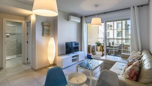 A modern living room with a sofa, TV, and dining area. - Las Arenas - Haraganes Beach HLHA181P193 (Isla Canela)