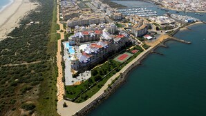 An aerial view of a coastal hotel with multiple buildings, a beach, and a marina. - Las Arenas - Haraganes Beach HLHA181P193 (Isla Canela)