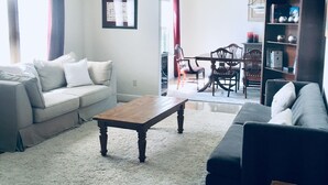 A living room with a sofa, a coffee table, and a bookshelf. - Sip, Swim, Sleep Soak,Escape! Lodi wineries minutes away (Lockeford)