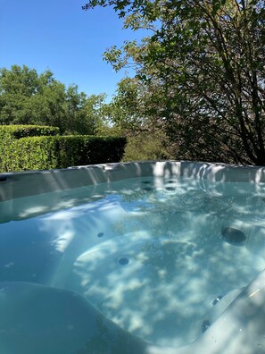Een hottub omringd door weelderige begroeiing en bomen.