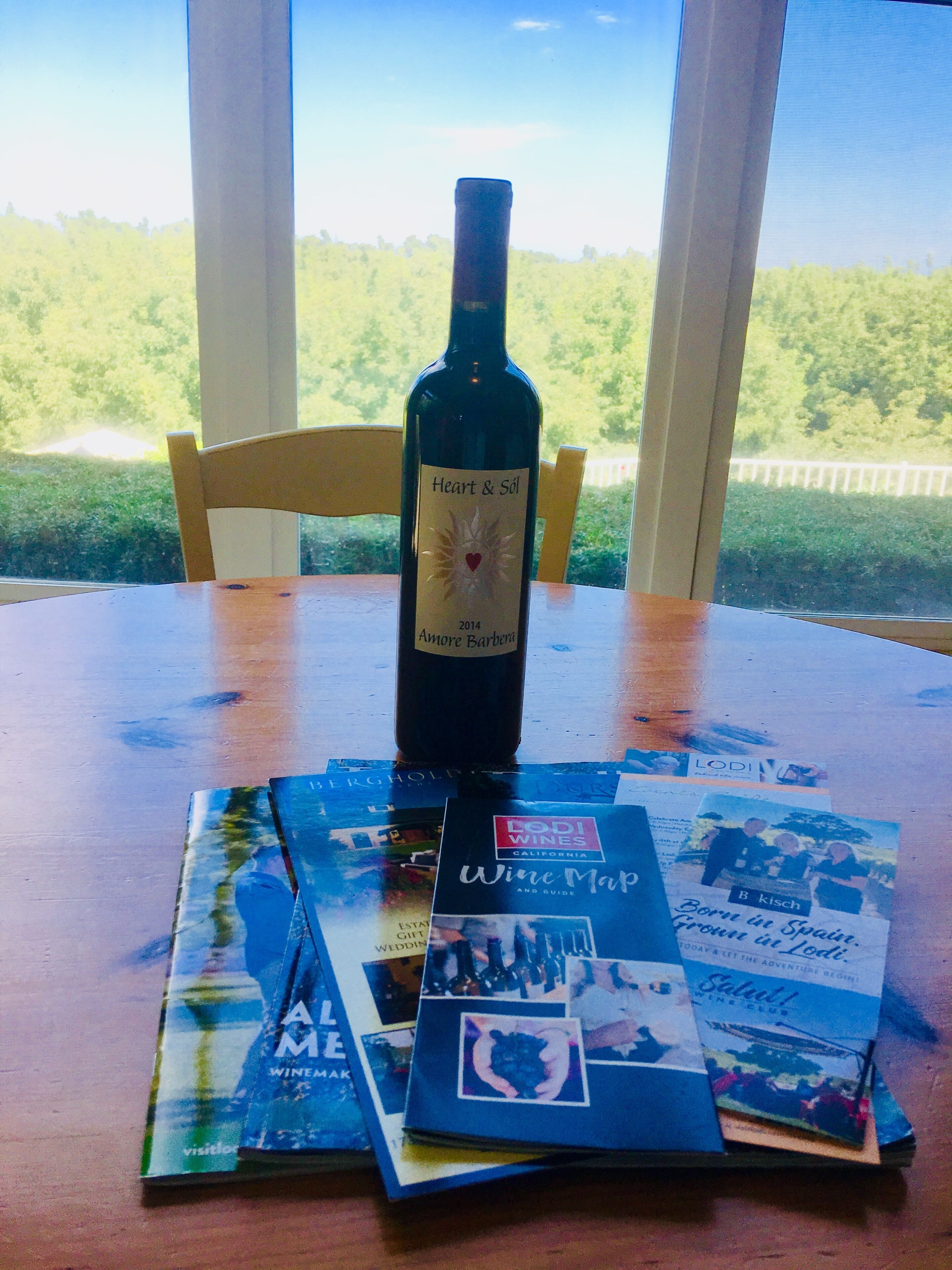 Una botella de vino sobre una mesa con folletos y un mapa.