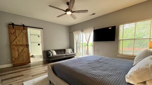 A bedroom with a bed, a ceiling fan, a window with curtains, a TV on the wall, and a sliding door. - Sip, Swim, Sleep Soak,Escape! Lodi wineries minutes away (Lockeford)