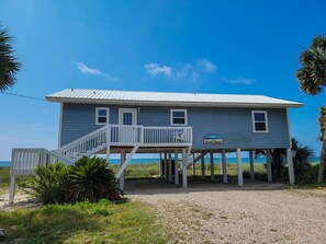 A two-story beachfront house with a balcony and a sign reading "Good Times."
