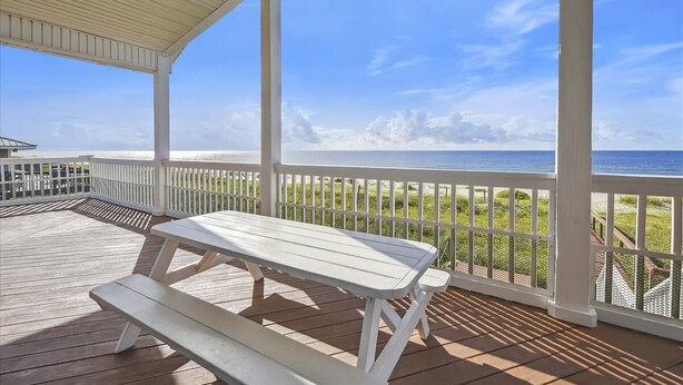 A covered deck with a picnic table and benches overlooking a beach. - YOU WILL INDEED be on Cloud Nine when you stay in this beautiful, beachfront home. (St. George Island)