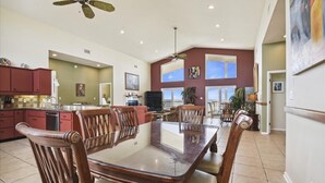 A spacious kitchen with a dining area, large windows, and a ceiling fan. - YOU WILL INDEED be on Cloud Nine when you stay in this beautiful, beachfront home. (St. George Island)