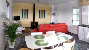 Ein modernes Wohnzimmer mit Essbereich, einer Couch, einem Fernseher und einem Kamin.