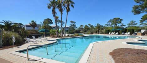 A pool area with lounge chairs and palm trees.