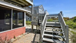 A coastal house with a wooden deck and a staircase leading to a balcony. - Cozy Cabanas East. A newly renovated ground level duplex. (St. George Island)