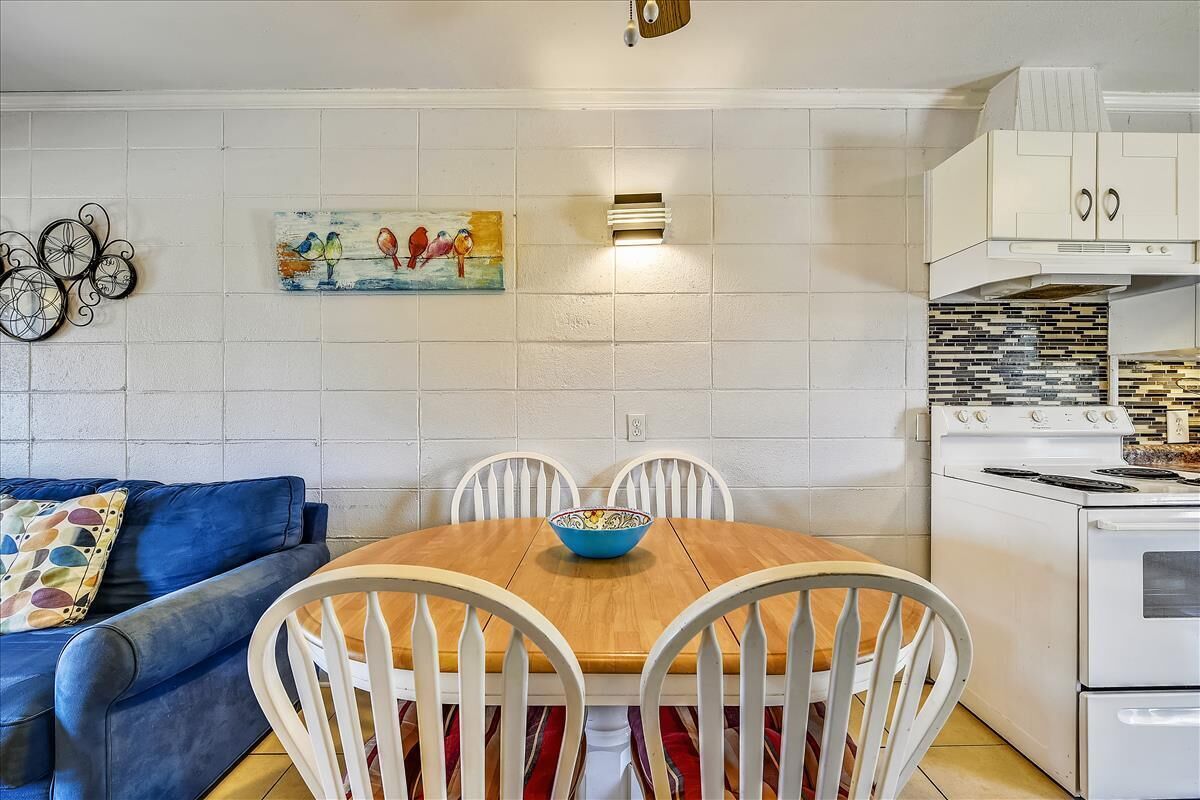 Une cuisine avec une table à manger, des chaises, une cuisinière et un saladier bleu.