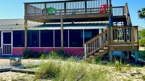 A two-story beach house with a wooden deck, a staircase, and large windows. - Cozy Cabanas East. A newly renovated ground level duplex. (St. George Island)