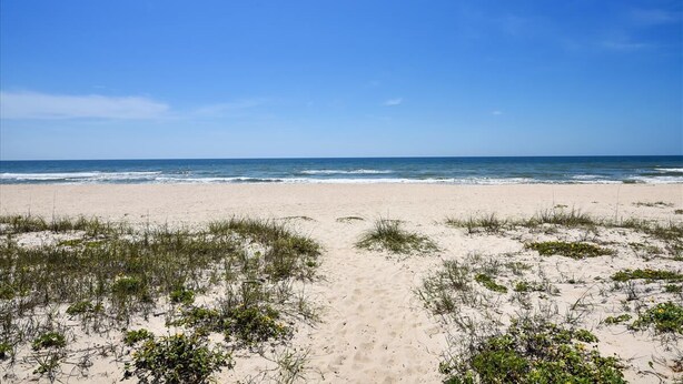 A beach with a clear sky and ocean in the background. - Cozy Cabanas East. A newly renovated ground level duplex. (St. George Island)